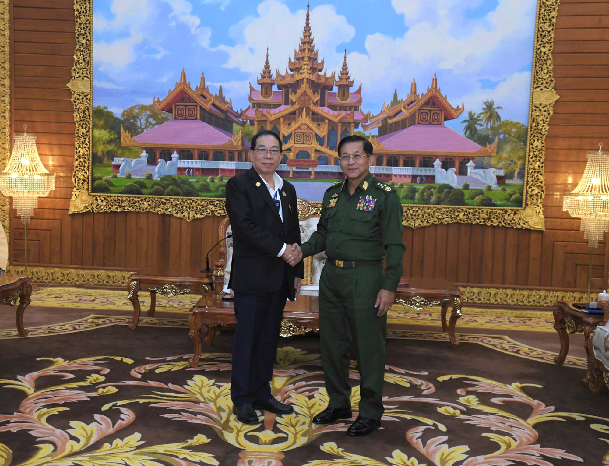 In this photo provided by the Myanmar Military True News Information Team, Senior Gen. Min Aung Hlaing, right, head of the military council, shakes hand with Yawd Serk, chairman of Shan State Army, during their meeting Friday, May 20, 2022, in Naypyitaw, Myanmar. (Military True News Information Team via AP)