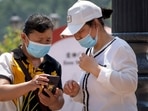 Women wearing face masks look at a smartphone at a shopping mall where most shops remain closed due to Covid-19 restrictions in Beijing. Women wearing face masks look at a smartphone at a shopping mall where most shops remain closed due to Covid-19 restrictions in Beijing.