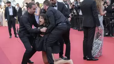 Guards removing a protester from the red carpet of the ongoing Cannes Film Festival on Friday.