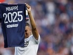 Paris St Germain's Kylian Mbappe holds up a shirt after signing a new contract(REUTERS)