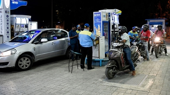 An attendant refills a two-wheeler with fuel while others wait in a queue as Government reduces central excise duty on petrol, diesel, (ANI Photo)(Ishant Kumar )