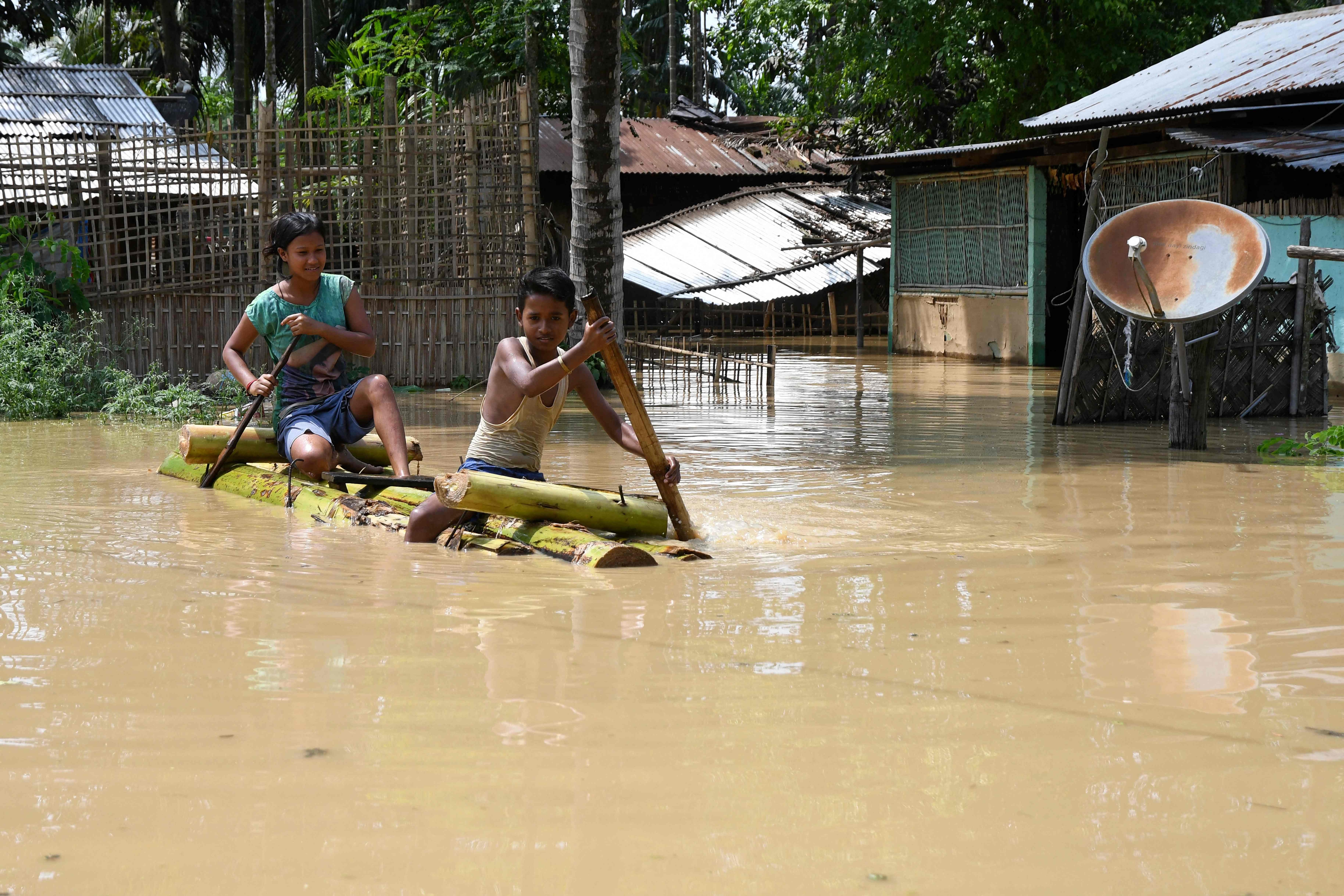 Children ride a bamboo raft through a flooded area after heavy rainfall in Morigaon district of Assam state on Sunday. (AFP) Children ride a bamboo raft through a flooded area after heavy rainfall in Morigaon district of Assam state on Sunday. (AFP)