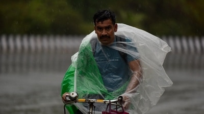 A person covers himself in a plastic sheet as cover from the rain. In Noida on Monday. (Sunil Ghosh / HT Photo). A person covers himself in a plastic sheet as cover from the rain. In Noida on Monday. (Sunil Ghosh / HT Photo).