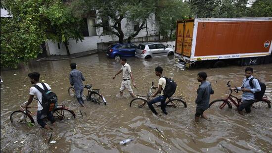 People wade through water near Galleria Market in Sushant Lok in Gurugram on Monday. (Vipin Kumar/ Hindustan Times)