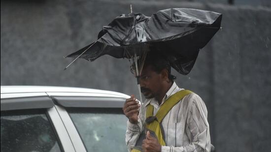 A commuter protects himself from gusty winds and heavy rainfall in Delhi NCR on Monday. (PTI Photo)