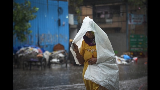 A commuter out in the rain, Shadipur, New Delhi, India, May 23, 2022 (Sanchit Khanna/Hindustan Times)