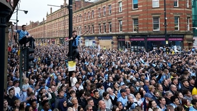 Fans gather to watch the Manchester City winners parade as the team celebrates winning the English Premier League title (AP)