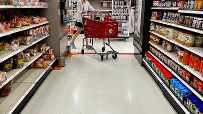 A woman pushes a shopping cart through the grocery aisle. (Photo by Jim WATSON / AFP) (AFP)