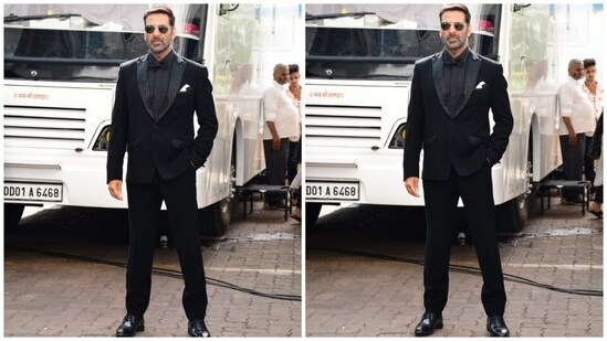 Akshay Kumar accompanied Manushi in an all-black tuxedo featuring a blazer with notch lapel embellished collars, padded shoulders and patch pockets. The actor teamed the jacket with matching black straight-fit pants, a silk shirt and a bow tie, rounding it all off with a sleek side-parted hairdo, sunglasses, matching dress shoes and a rugged beard.(HT Photo/Varinder Chawla)