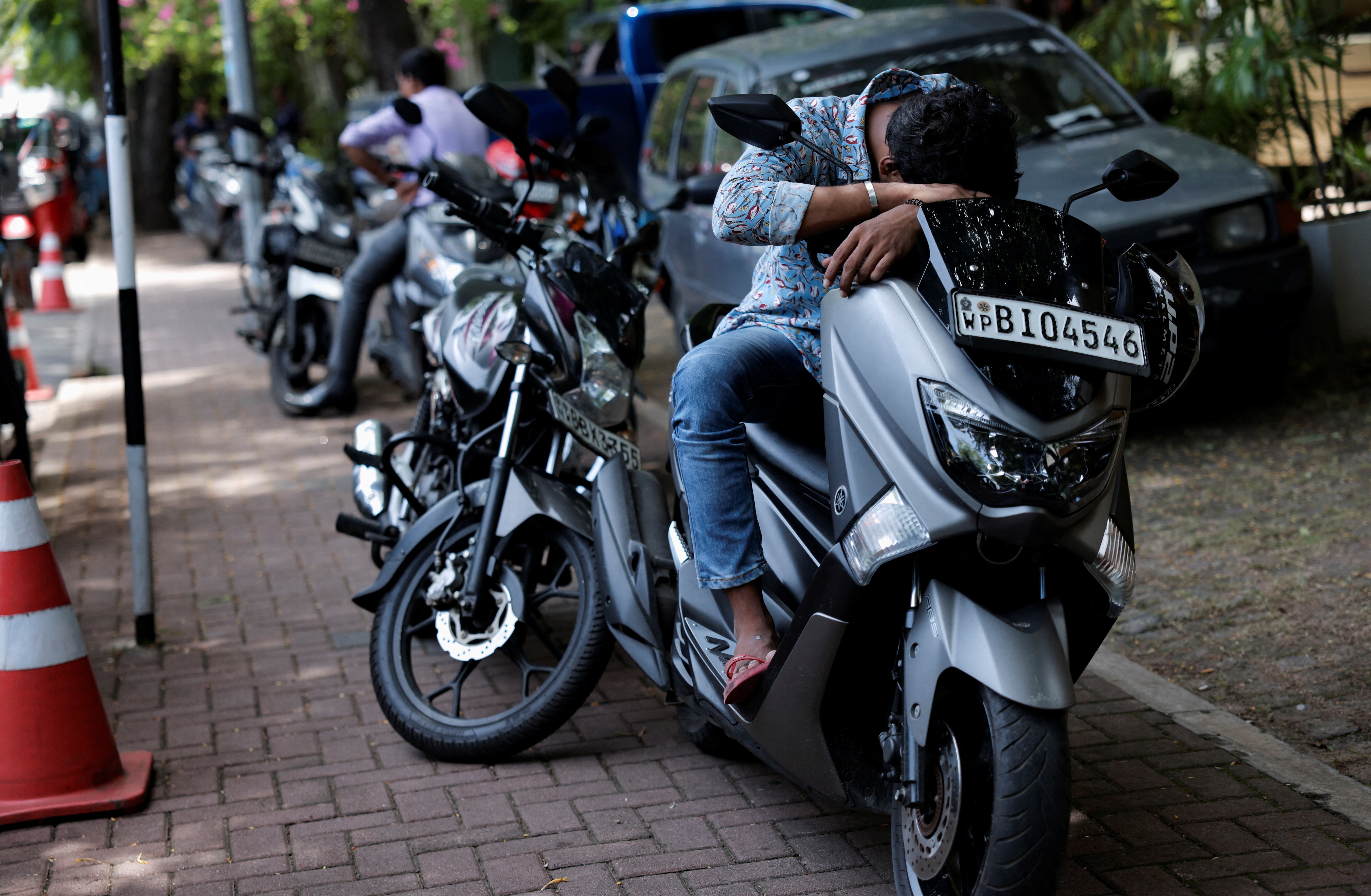 A man sleeps on his bike as he waits in a line to buy petrol near a fuel station, amid the country's economic crisis, in Colombo, Sri Lanka. (REUTERS)