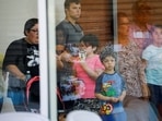 A child looks on through a glass window from inside the Ssgt Willie de Leon Civic Center, where students had been transported from Robb Elementary School after a shooting, in Uvalde, Texas.&nbsp;