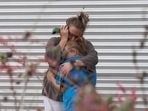 A woman cries and hugs a young girl while on the phone outside the Willie de Leon Civic Center where grief counseling will be offered in Uvalde, Texas.