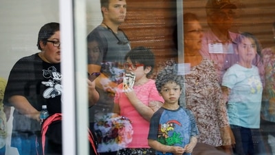 A child looks on through a glass window from inside the Ssgt Willie de Leon Civic Center, where students had been transported from Robb Elementary School after a shooting, in Uvalde, Texas.&nbsp; (REUTERS)