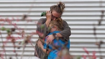 A woman cries and hugs a young girl while on the phone outside the Willie de Leon Civic Center where grief counseling will be offered in Uvalde, Texas. (AFP)