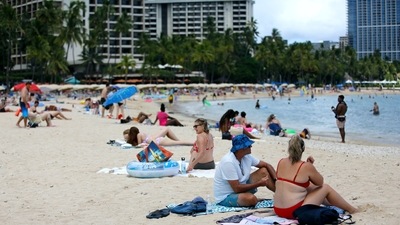Tourists from Australia sit on Waikiki Beach in Honolulu. Covid case counts are as high as they've been since mid-February and those figures are likely a major undercount because of unreported home tests and asymptomatic infections but the beaches beckoned and visitors have flocked to Hawaii, especially in recent months. (AP Photo/Caleb Jones) Tourists from Australia sit on Waikiki Beach in Honolulu. Covid case counts are as high as they've been since mid-February and those figures are likely a major undercount because of unreported home tests and asymptomatic infections but the beaches beckoned and visitors have flocked to Hawaii, especially in recent months. (AP Photo/Caleb Jones)