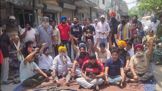 Residents and shopkeepers of Khud Mohalla area, Ludhiana, block the main road during the protest against installation of mobile tower. (Harvinder Singh/HT)
