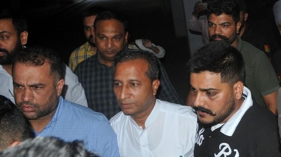 Sacked Punjab health minister Dr Vijay Singla (in white) being escorted out of the district court complex in Mohali on Wednesday, May 25, 2022. He was remanded in police custody till May 27. (Ravi Kumar/HT)