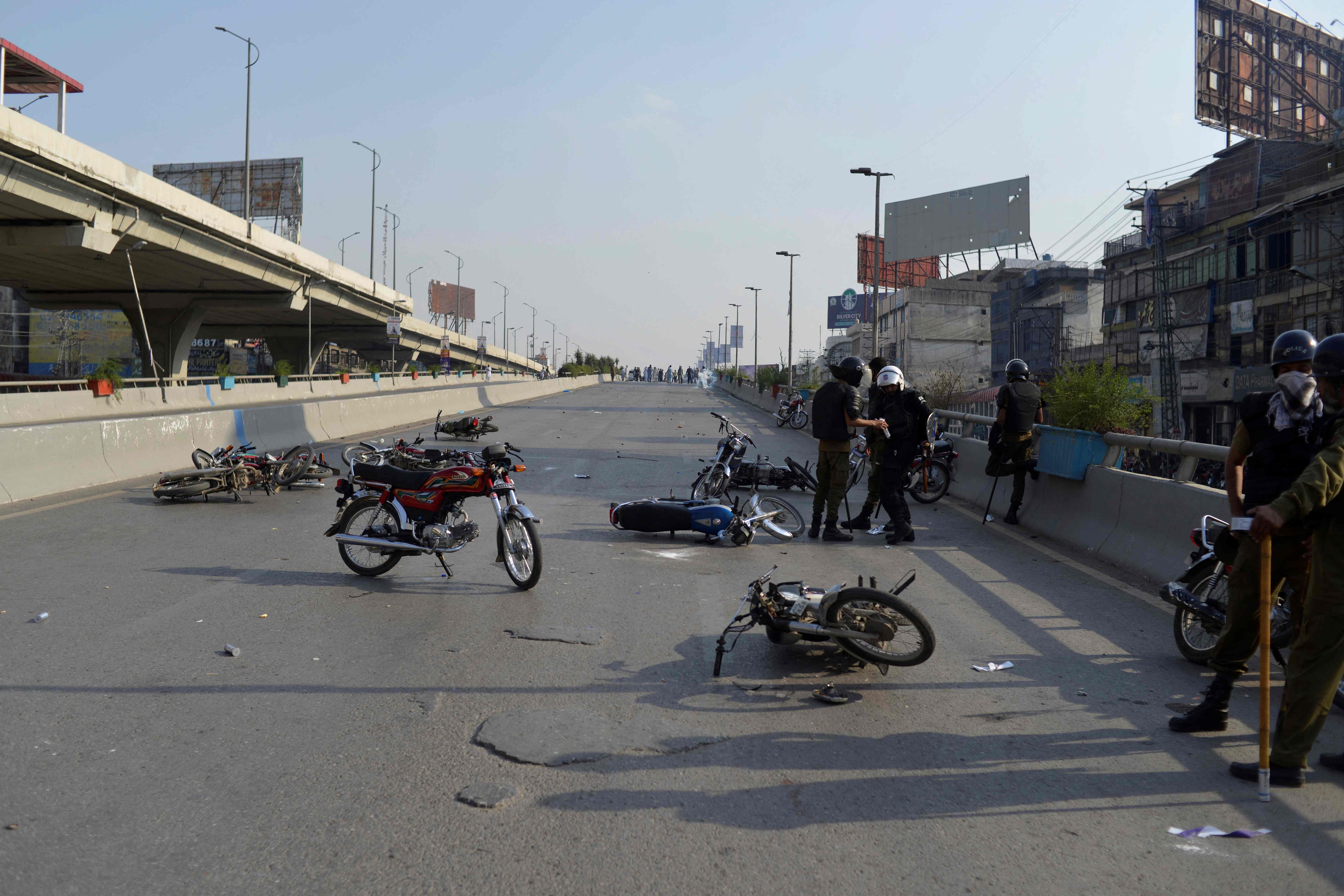 수요일 라왈핀디에서 시위대와 경찰이 충돌하는 동안 경찰관들이 손상된 오토바이 옆에 서 있다.