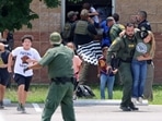 Children run to safety after escaping from a window during a mass shooting at Robb Elementary School where a gunman killed nineteen children and two adults in Uvalde, Texas, U.S. May 24.