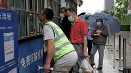 Pessoas fazem fila para serem testadas para o coronavírus Covid-19 em um local de coleta de zaragatoas em Pequim no domingo.