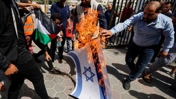 Palestinos queimam uma representação de uma bandeira israelense durante um protesto contra as tensões na mesquita de Al-Aqsa, em Jerusalém, em Khan Younis, no sul da Faixa de Gaza, no domingo. 