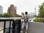 A resident takes a photograph while standing being barriers blocking access across a bridge in Shanghai, China, on Monday, May 30, 2022. China reported the fewest new Covid-19 cases in almost three months, with the easing of outbreaks in Shanghai emboldening authorities to relax some of the strictest virus controls of the pandemic and move to stimulate the country's faltering economy. A resident takes a photograph while standing being barriers blocking access across a bridge in Shanghai, China, on Monday, May 30, 2022. China reported the fewest new Covid-19 cases in almost three months, with the easing of outbreaks in Shanghai emboldening authorities to relax some of the strictest virus controls of the pandemic and move to stimulate the country's faltering economy. 