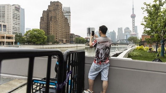 A resident takes a photograph while standing being barriers blocking access across a bridge in Shanghai, China, on Monday, May 30, 2022. China reported the fewest new Covid-19 cases in almost three months, with the easing of outbreaks in Shanghai emboldening authorities to relax some of the strictest virus controls of the pandemic and move to stimulate the country's faltering economy. (Bloomberg)