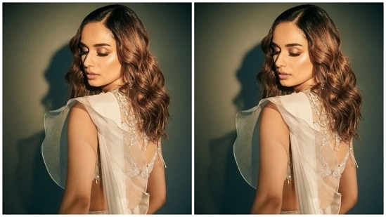 Manushi paired the six yards with a white sleeveless hand-embellished blouse featuring a plunging V neckline, intricate thread embroidery, sequinned patterns, tassel adornments and pearl decorations. It also comes with a unique back adorned with a cut-out, sheer panelling and heavy embellishments.(Instagram)