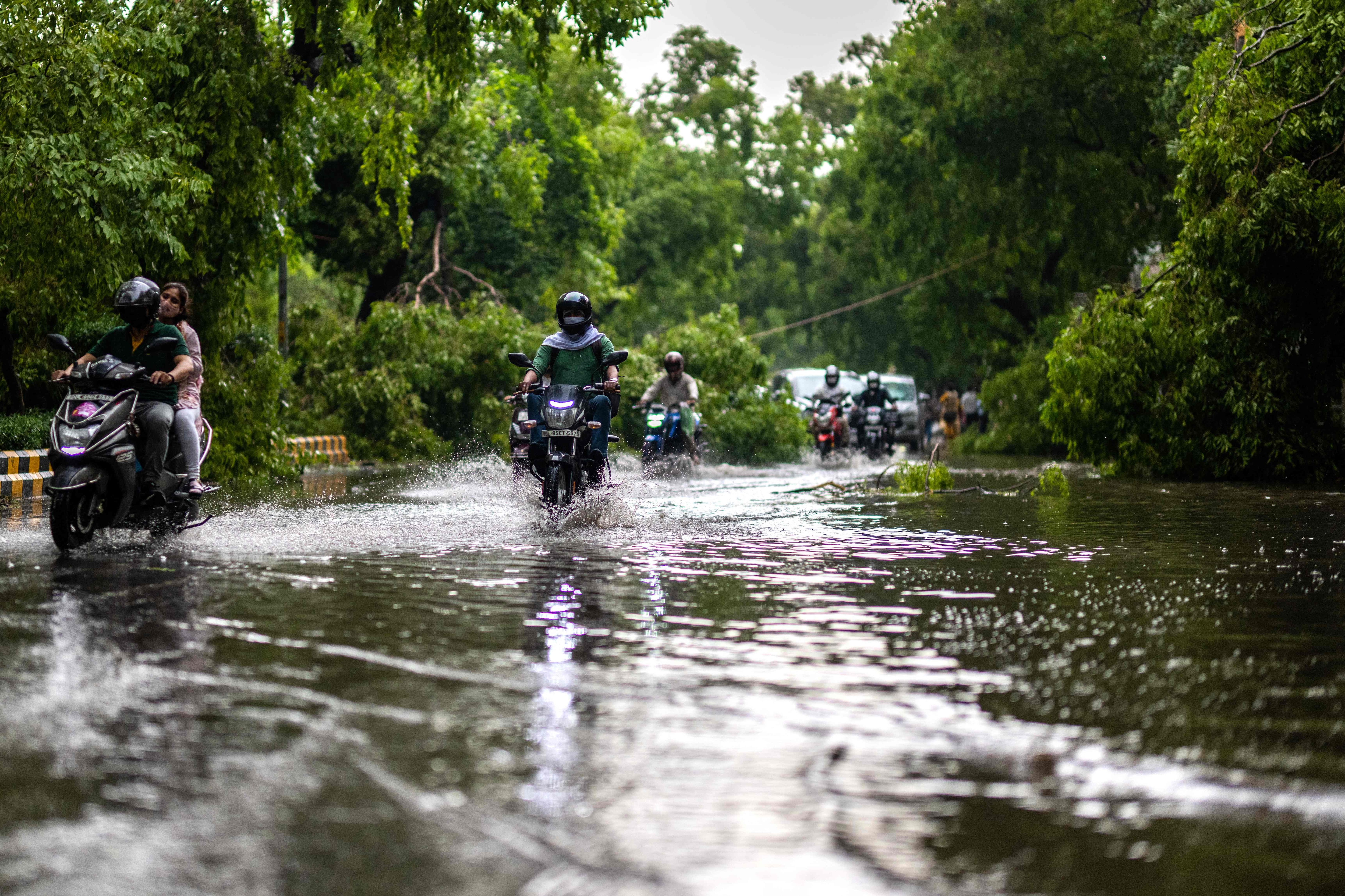 Commuters drive past a fallen tree branch on a waterlogged street after a storm in New Delhi on May 30, 2022. (AFP) Commuters drive past a fallen tree branch on a waterlogged street after a storm in New Delhi on May 30, 2022. (AFP)