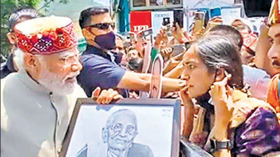 A woman presents a sketch of Prime Minister Narendra Modi's mother to him during a road show in Shimla on Tuesday.
