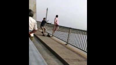 Grab from the viral video showing the unidentified youth grabbing the woman and pulling her down from the railing of the New Yamuna Bridge in Prayagraj (HT PHOTO)