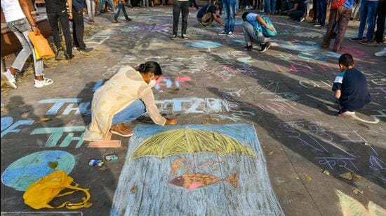 Students participate in drawing chalk graffiti art to make people aware of the climate crisis, at Connaught place in New Delhi. (ANI)