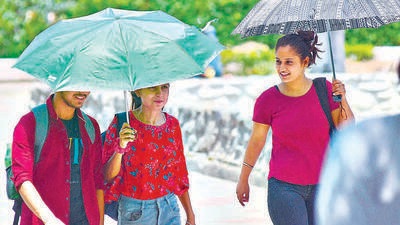 Students taking refuge under umbrellas amid the sweltering weather on the Panjab University campus in Chandigarh on Thursday. (Keshav Singh/HT)