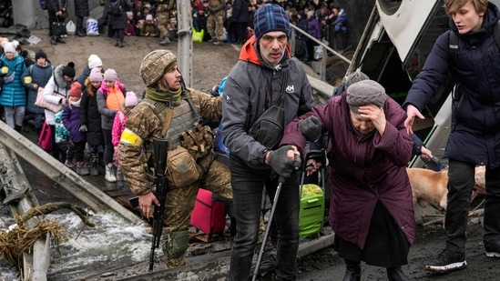 An elderly woman is assisted to cross the Irpin River on an improvised path under a bridge that was destroyed by Ukrainian troops to slow the Russian military advance while fleeing the town of Irpin, Ukraine, Saturday, March 5, 2022. (AP Photo/Vadim Ghirda, File) (AP)