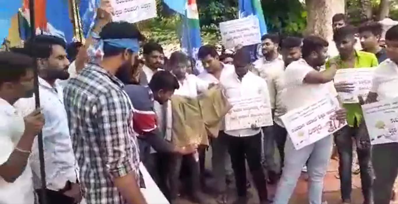 NSUI members lit a pair of khaki shorts on fire in front of Karnataka Education Minister B C Nagesh's home in Tumkur on Wednesday in protest of revisions made to school textbooks. NSUI members lit a pair of khaki shorts on fire in front of Karnataka Education Minister B C Nagesh's home in Tumkur on Wednesday in protest of revisions made to school textbooks.