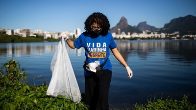 A volunteer collects garbage from the banks of the Rodrigo de Freitas Lagoon marking World Environment Day, in Rio de Janeiro, Brazil. (AP)