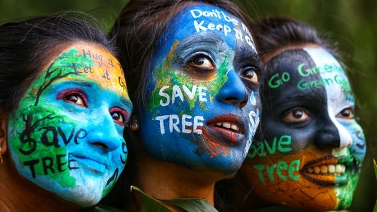 Girls paint their faces with the message of saving the environment, on the eve of the World Environment Day, in Nagpur, (PTI)