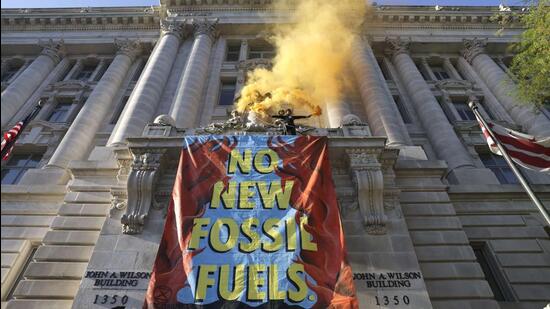 An environmental activist with the group Extinction Rebellion DC scales the Wilson Building as part of an Earth Day rally against fossil fuels in Washington, DC on April 22, 2022 . (AFP)