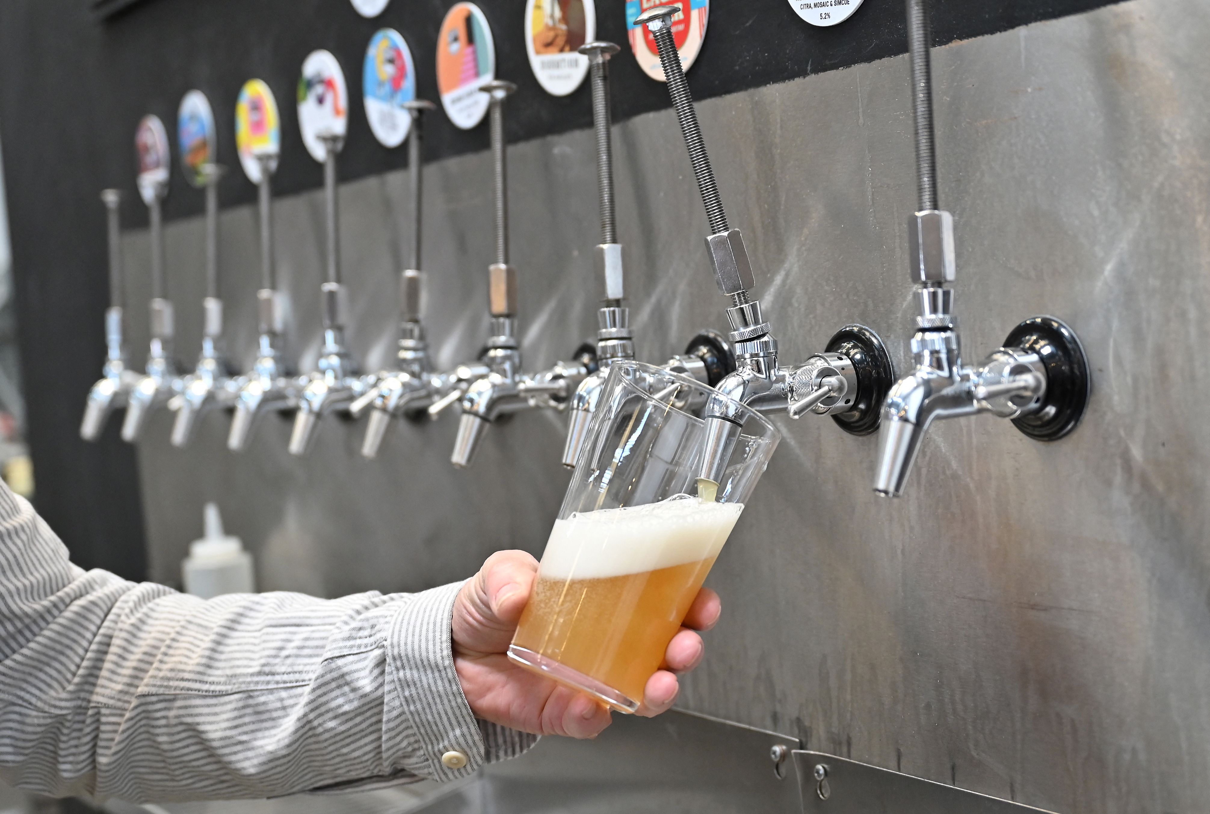 A worker pours a pint of beer at Pressure Drop Brewery, in north London, on May 21, 2022. (Photo by Justin TALLIS/AFP)