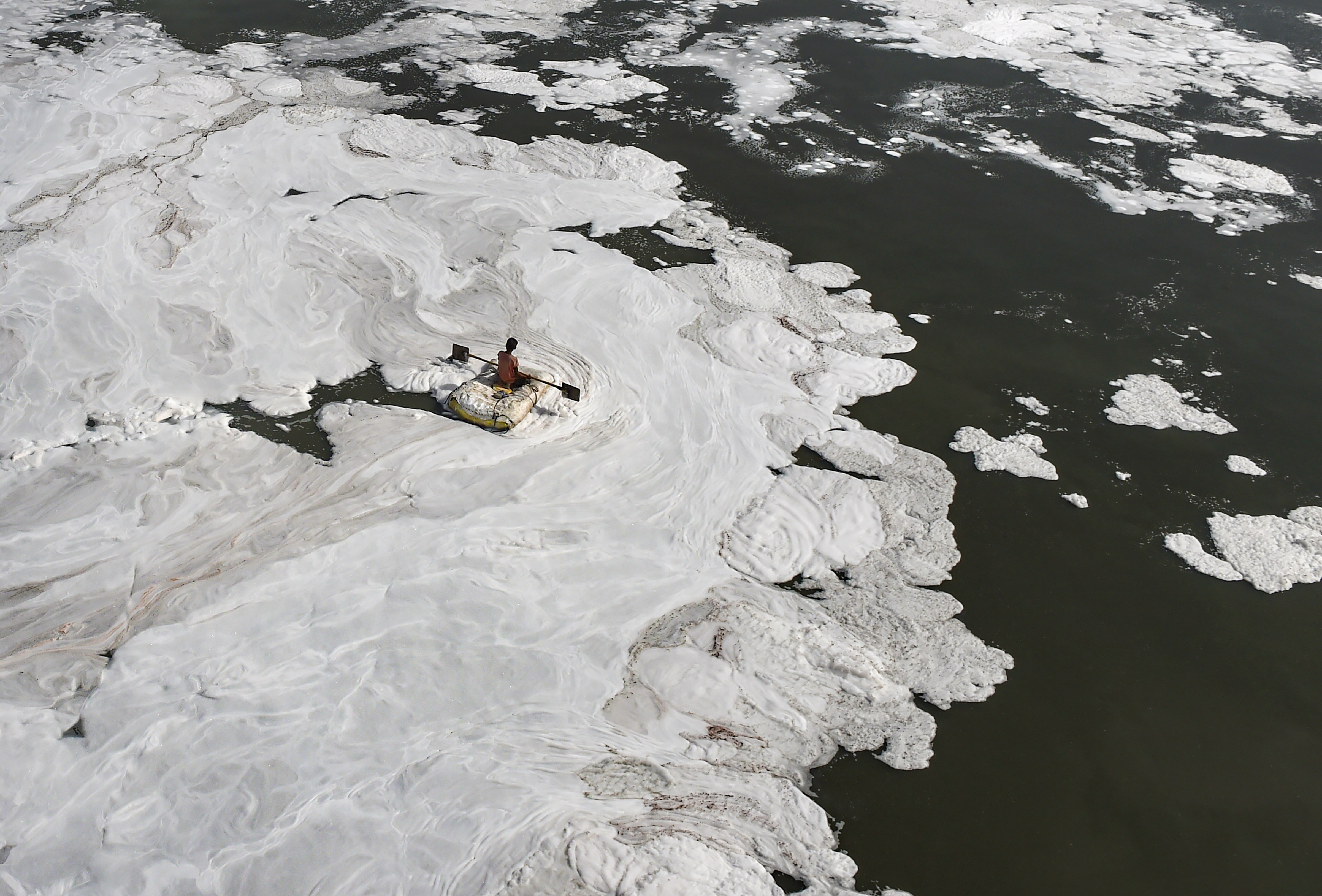 A man rides a makeshift boat through toxic foam floating in Yamuna river, on World Environment Day, at ITO, in New Delhi, Sunday. (PTI) A man rides a makeshift boat through toxic foam floating in Yamuna river, on World Environment Day, at ITO, in New Delhi, Sunday. (PTI)