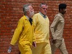 Jim Fitton of Britain, left, and Volker Waldmann of Germany, center, wearing yellow detainees’ uniforms and handcuffed are escorted by Iraqi security forces, outside a courtroom, in Baghdad, Iraq, Sunday.(AP)
