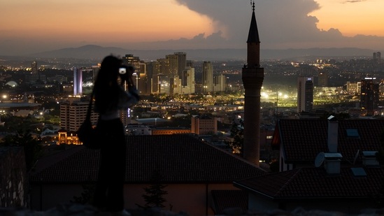 A visitor photographs the city skyline from Ankara castle at dusk in Ankara, Turkey. Turkey's inflation soared in May to the fastest since 1998 as it came under more pressure from the rising cost of food and energy while ultra-loose monetary policy contributed to currency weakness. (Photographer: SeongJoon Cho/Bloomberg)