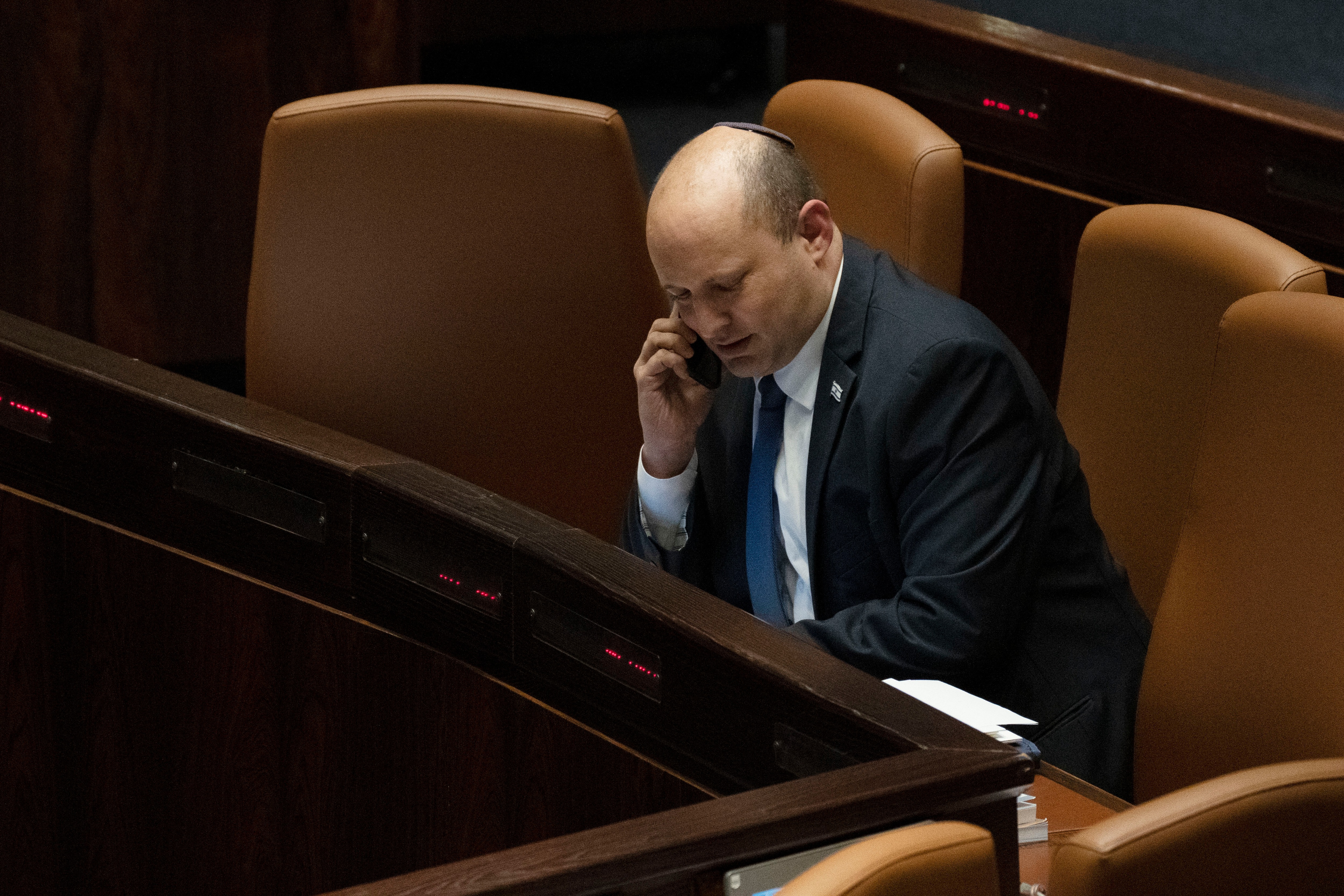 Israeli PM Naftali Bennett makes a call before voting on a law on the legal status of Jewish settlers in the occupied West Bank, during a session of the Knesset, in Jerusalem, on June 6, 2022. (AP) Israeli PM Naftali Bennett makes a call before voting on a law on the legal status of Jewish settlers in the occupied West Bank, during a session of the Knesset, in Jerusalem, on June 6, 2022. (AP)