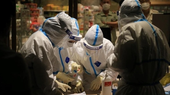 Health workers carrying out coronavirus tests in a shopping mall in Dalian (STR / AFP)