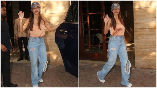 Malaika donned a silk satin peach-coloured crop top featuring a plunging neckline, strapped sleeves and a cropped hem length, showing a hint of her toned midriff. The star teamed it with high-waisted denim jeans with flared hem and distressed details.(HT Photo/Varinder Chawla)