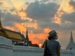 A tourist wears a face mask to prevent spread of the coronavirus disease (Covid-19) during sunset near the Grand Palace in Bangkok, Thailand. (REUTERS/Chalinee Thirasupa)