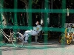 A worker in a protective suit sits at a sealed area, amid new lockdown measures in parts of the city to curb the coronavirus disease (Covid-19) outbreak in Shanghai, China.