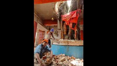 Workers making space in the roof to adjust a tree trunk and branches at Kali Ma temple at Chauphatka in Prayagraj. (HT photo) Workers making space in the roof to adjust a tree trunk and branches at Kali Ma temple at Chauphatka in Prayagraj. (HT photo)
