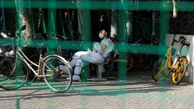 A worker in a protective suit sits at a sealed area, amid new lockdown measures in parts of the city to curb the coronavirus disease (Covid-19) outbreak in Shanghai, China. (REUTERS)