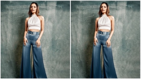 Manushi decked up in a white satin cropped top with halter neck and backless details, held in place with a knot detail at the back. She teamed her look with a pair of blue satin trousers with wide legs and a belt detail at the waist.(Instagram/@manushi_chhillar)